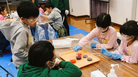 子どもたちがテーブルを囲んで化学の実験をする様子
